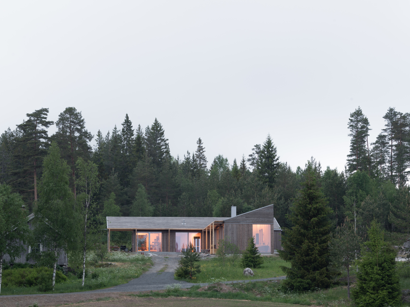 Eksteriørfoto av enebolig med trekledning omgitt av skog.