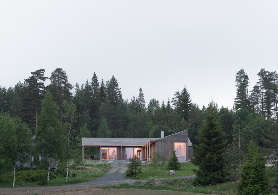 Eksteriørfoto av enebolig med trekledning omgitt av skog.