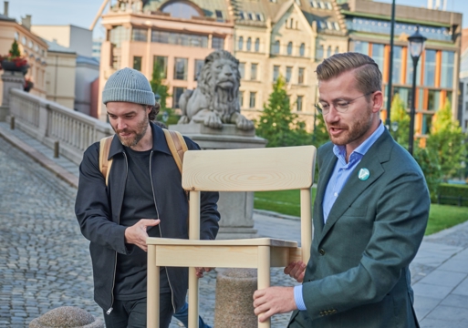 Bilde av designer og daværende miljøminister Sveinung Rotevatn (V) bære Nuen-stolen utenfor Stortinget.