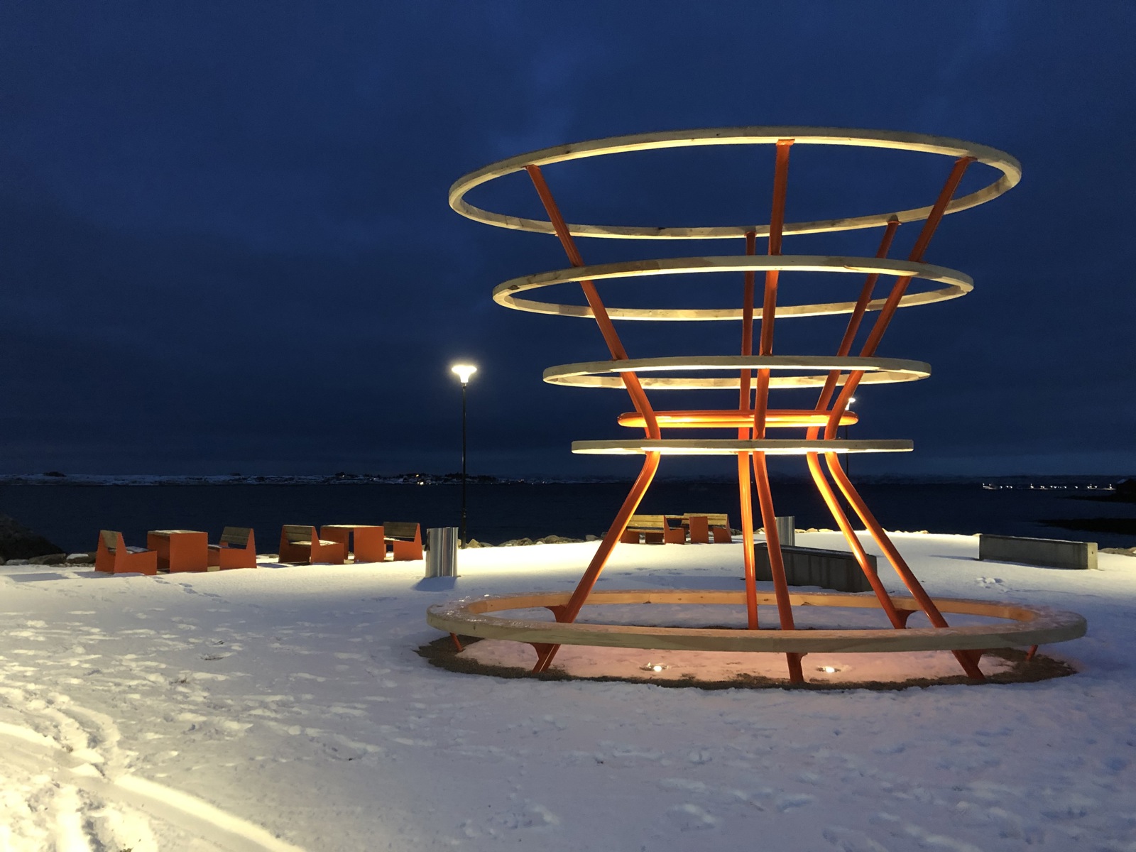 Foto av en kunstinstallasjon i offentlig rom, opplyst i vintermørke.