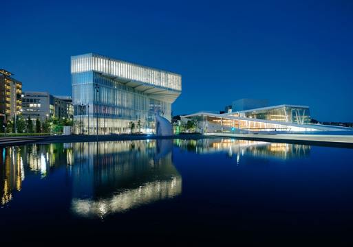 Foto av Deichmanske Bjørvika som speiles i vannet med Operaen på høyre side.