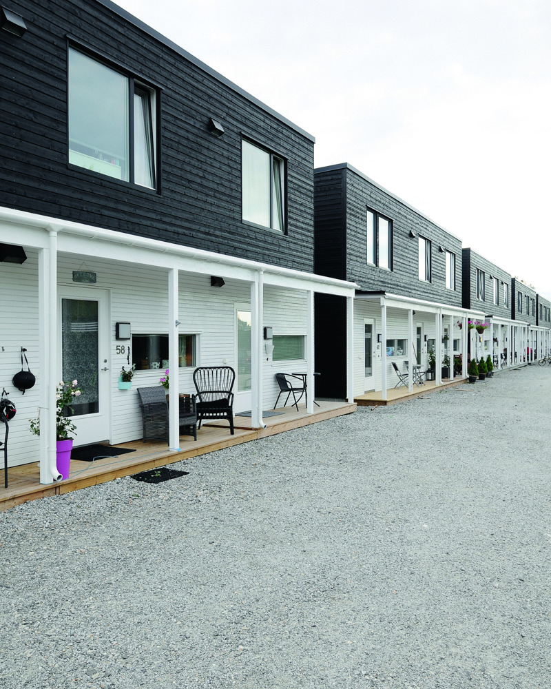 Rekkehus i svart og hvit panel, grus fremfor. Foto.