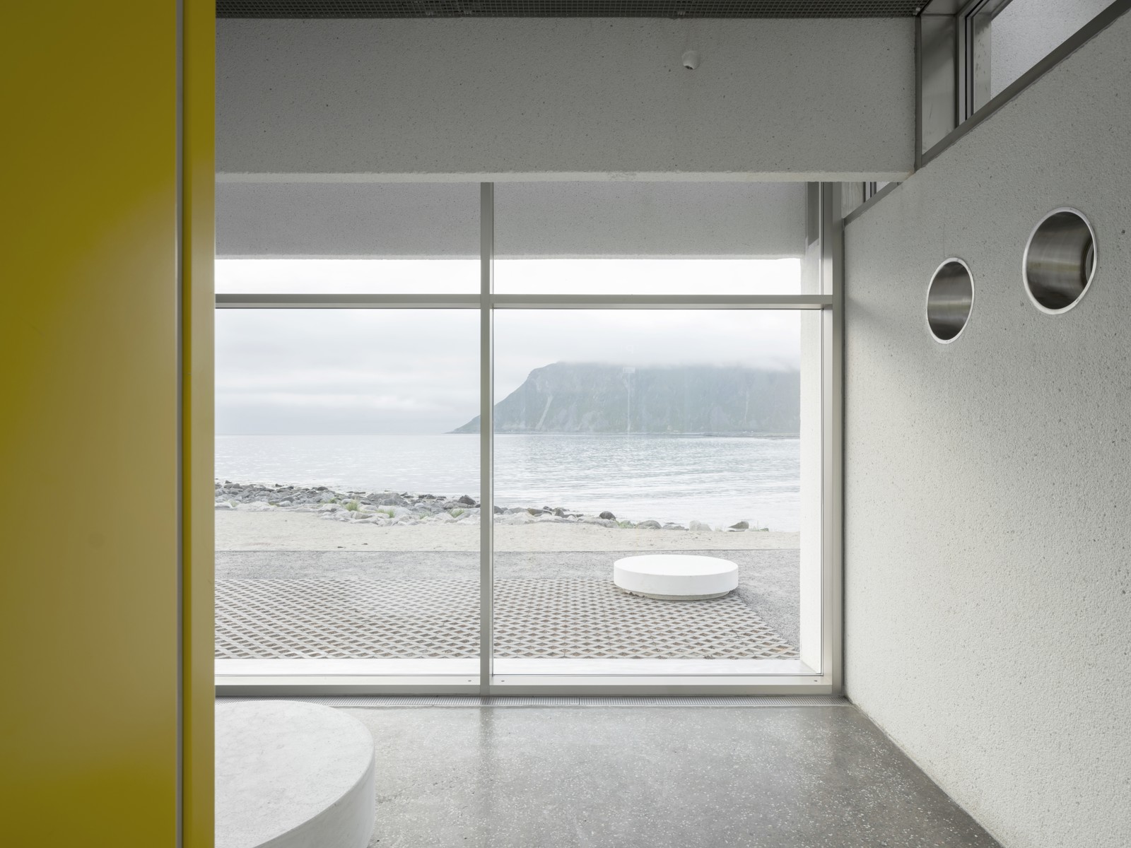 Interiør foto av servicebygg med store vinduer med utsikt til hav og fjell.