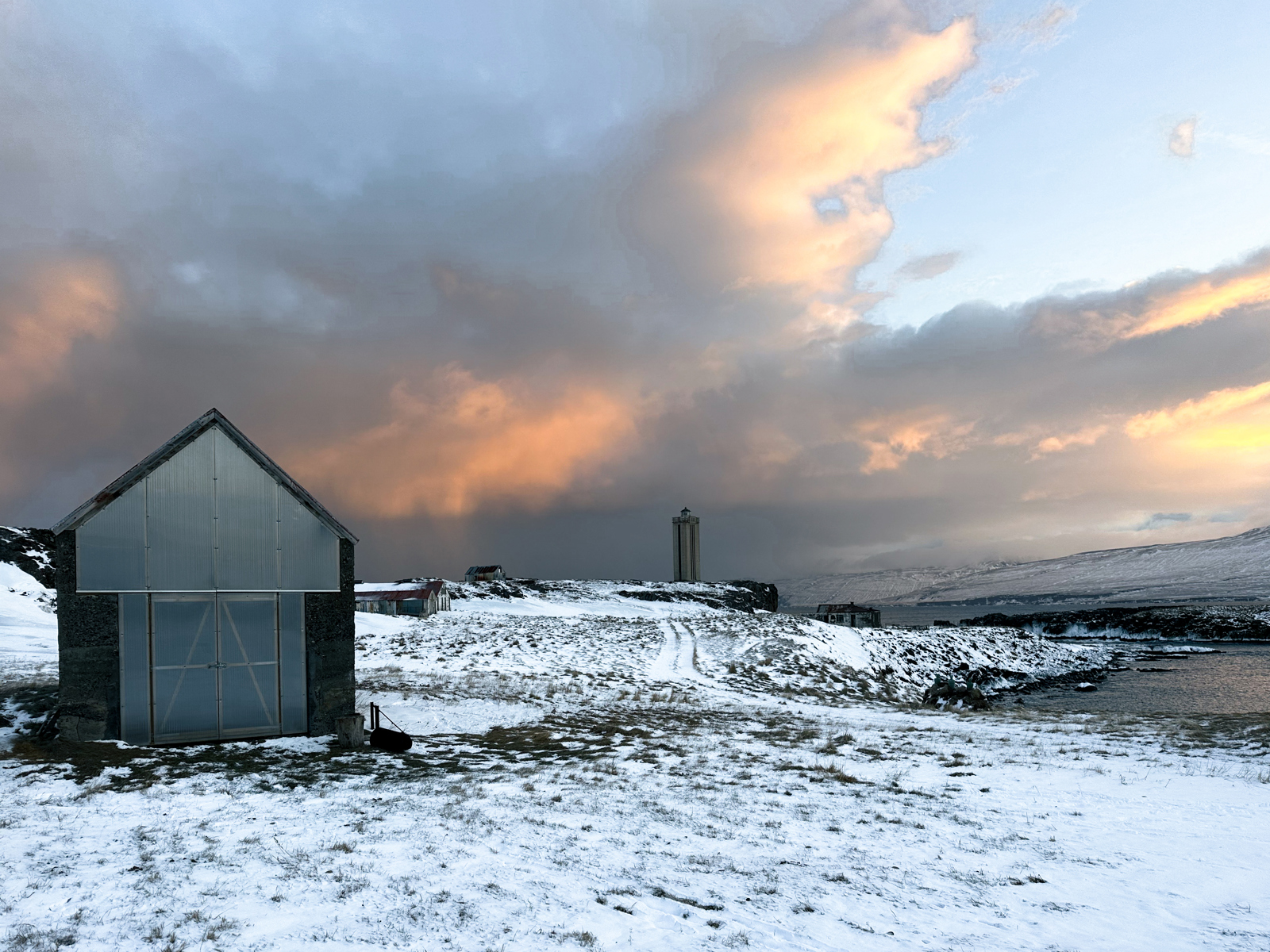 Foto av badstuehus i vinterlandskap, snø og hav.
