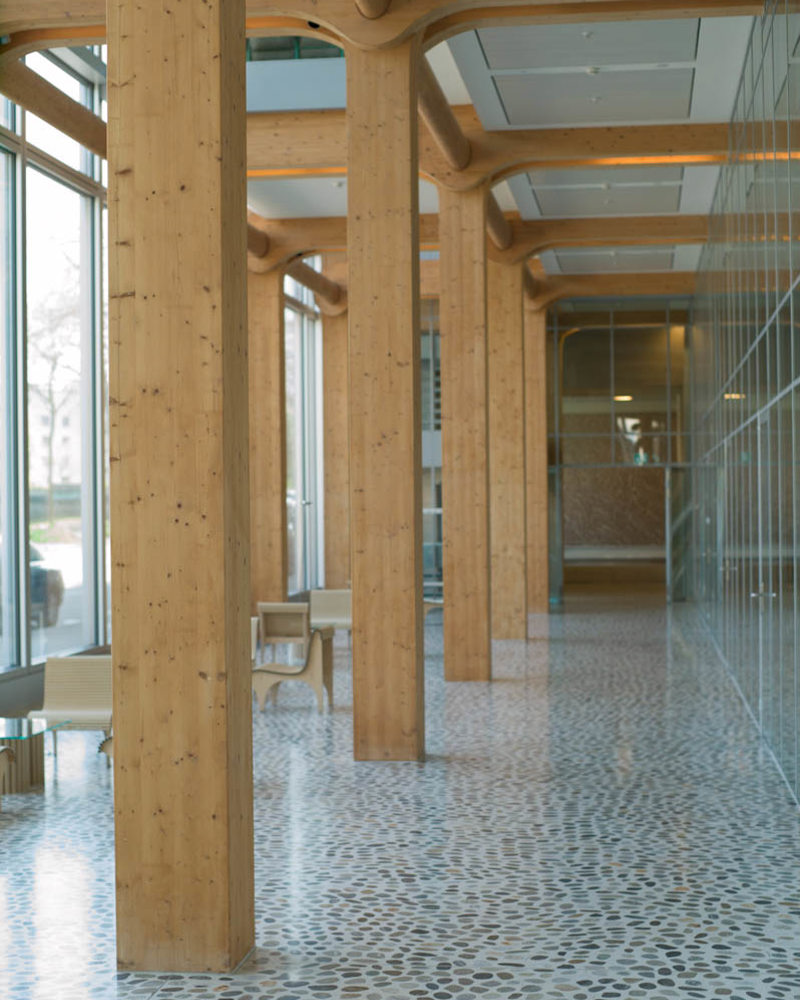 Interiør foto av lobby. Tresøyler, høyt under taket, terazzo gulv.