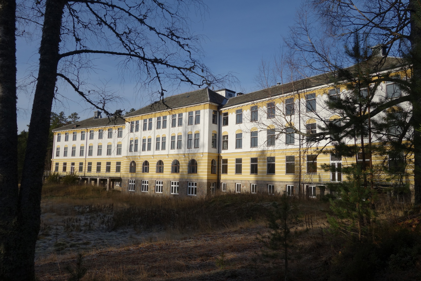Eksteriørfoto av sanatoriumets langstrakte fasade i gul, hvit pusset fasade.