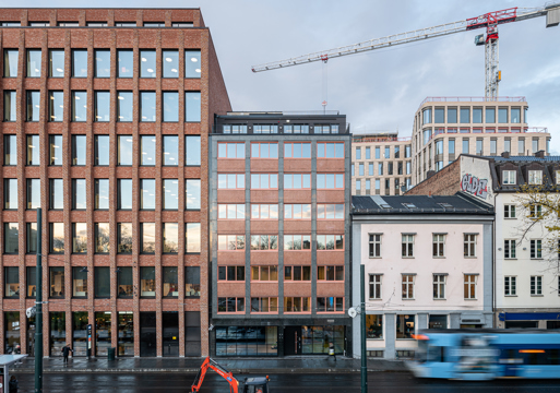 Foto av eksteriøret, streng rytmisk fasade av glass og tegl.