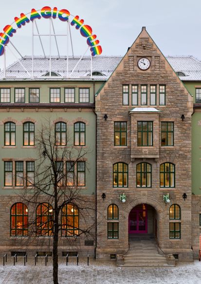 Fasade foto av bygg i jugendstil med et skilt på taket i regnbuefarger.