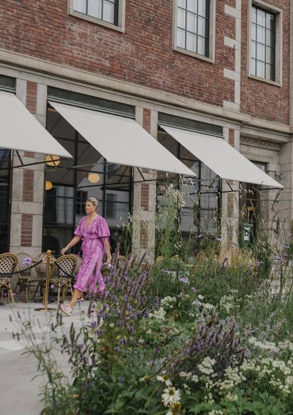 Foto av beplantning fremfor Sommerro, en kvinne i rosa kjole går i bakgrunnen.