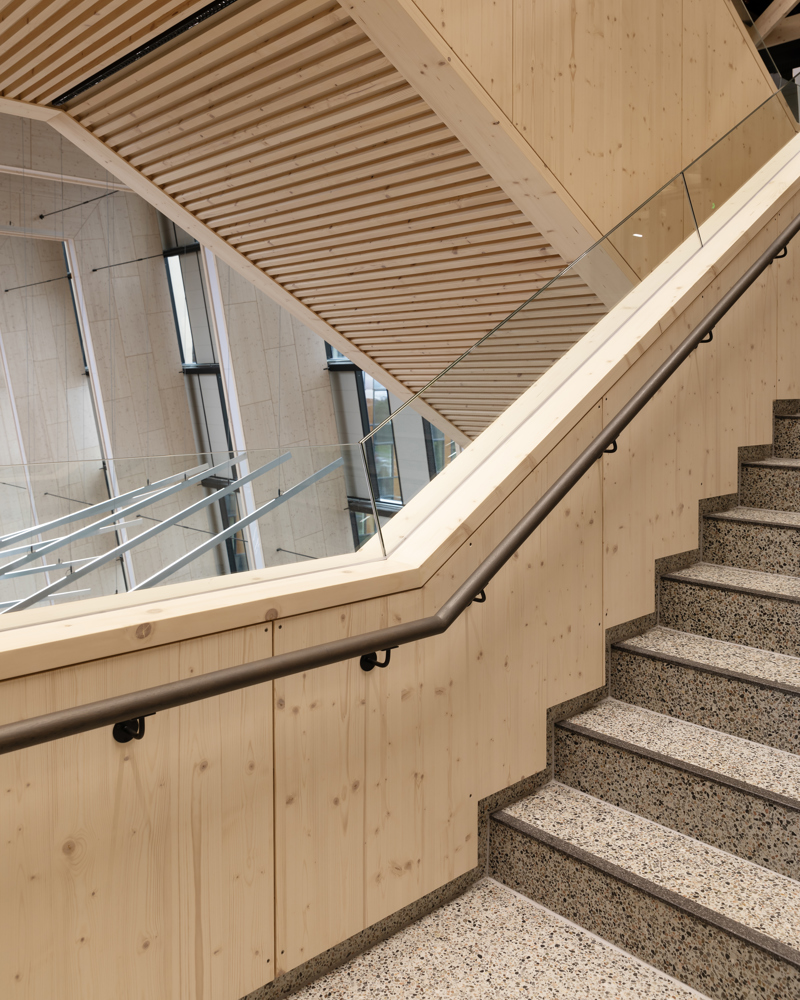 Foto av trapp med gelender i treverk og trappetrinn i terazzo.