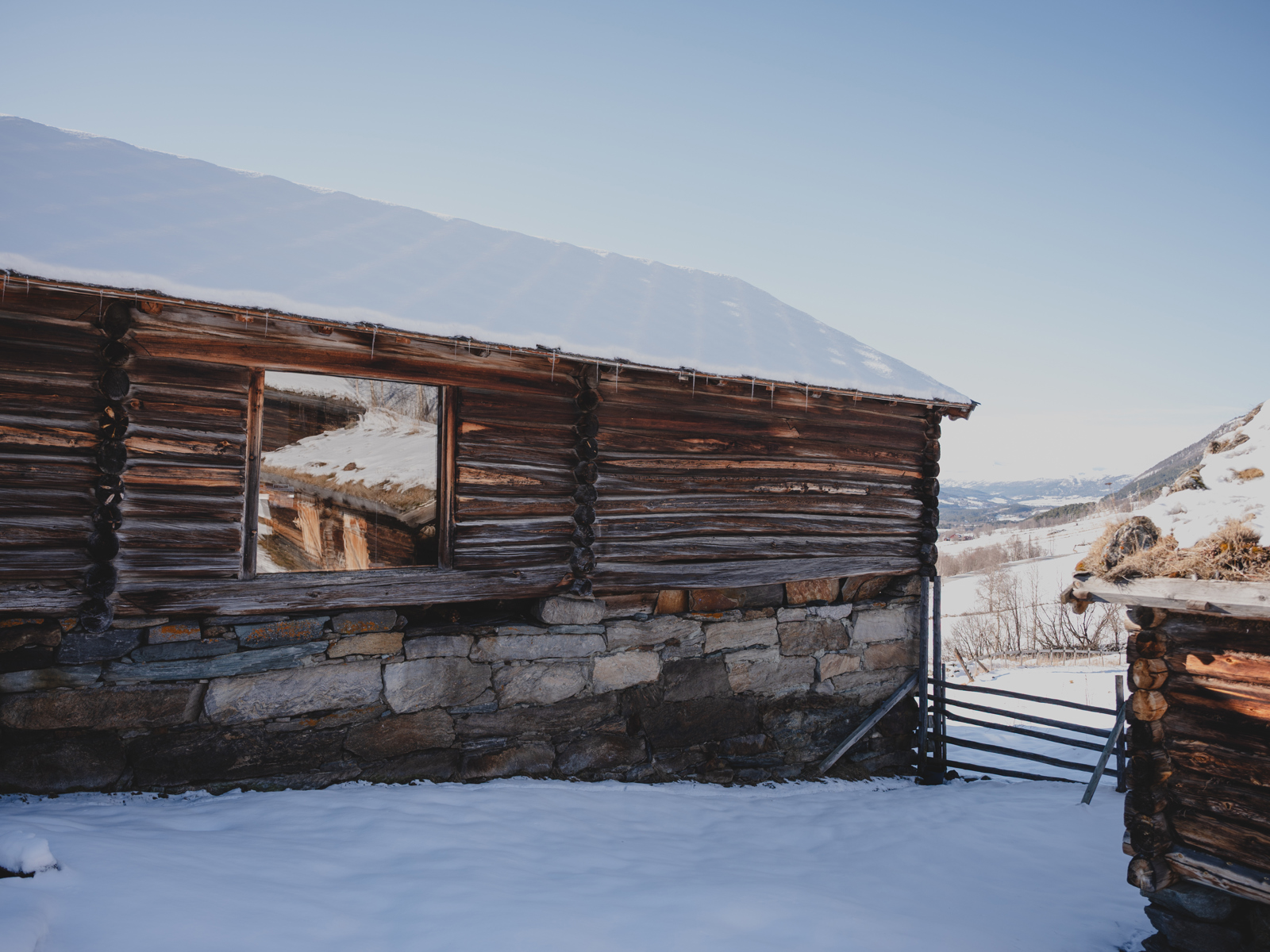 Foto av et laftebygg på steinmur med et større vindu i veggen.