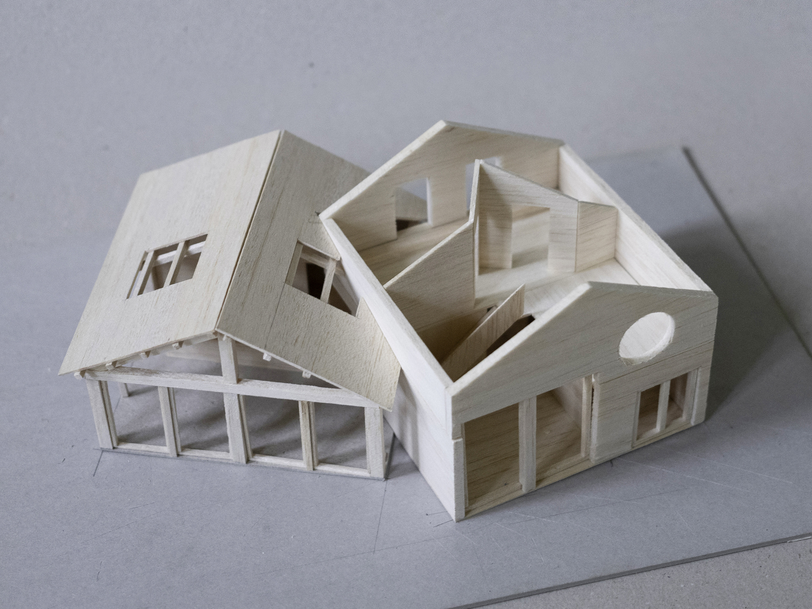 Modell i tre av to hus som kjærer inn i hverandre, taket er tatt av på det ene huset og man kan se innsiden. Foto.