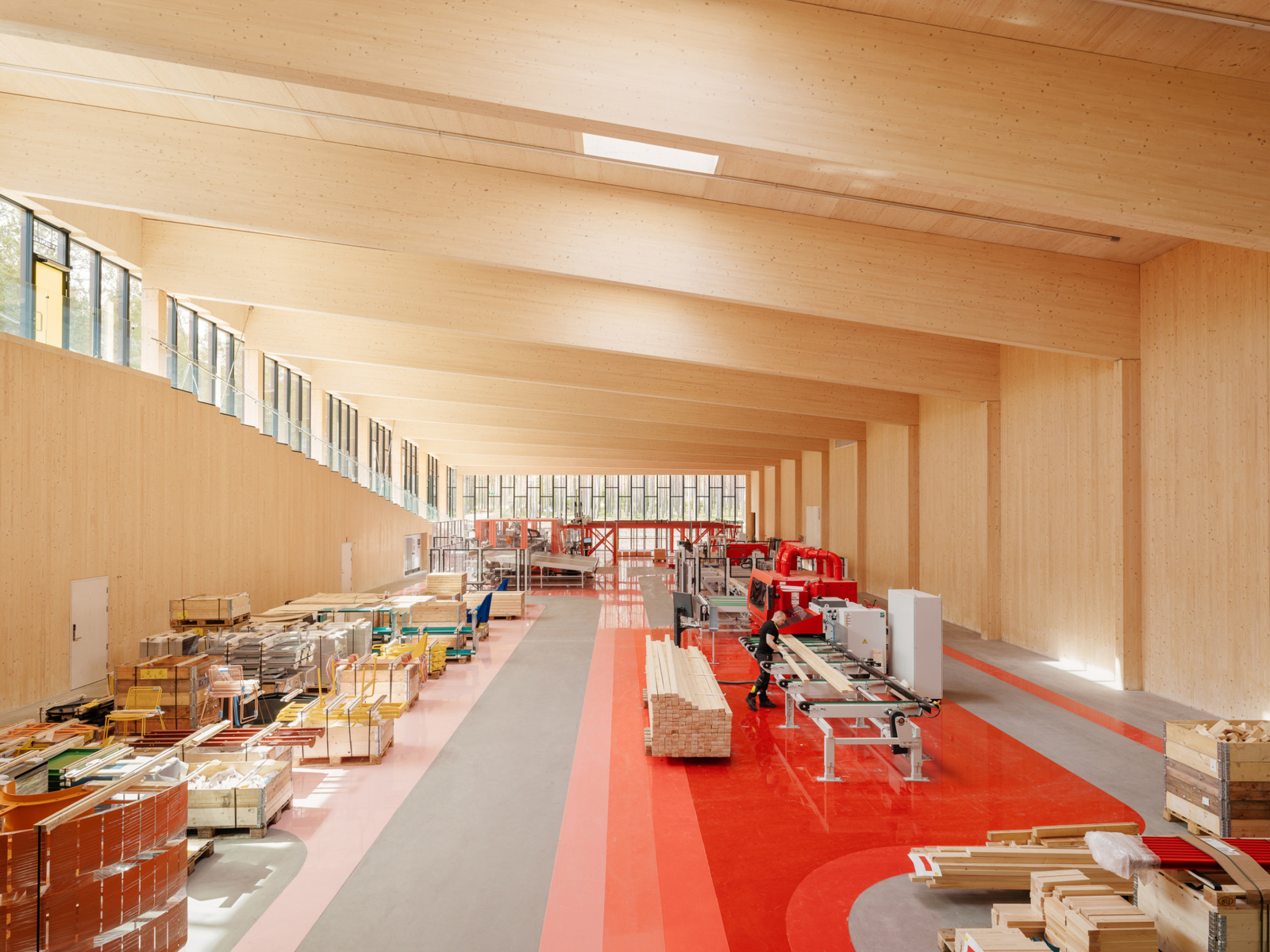 Interiør i treverk og rødfarger på gulv. Fabrikkhall. Foto.