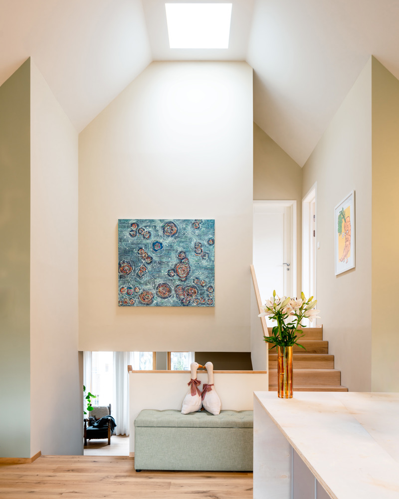 Interiørfoto av enebolig med dobbelthøyt fellesrom og duse farger.