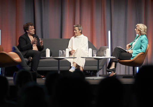 Tre mennesker sitter i en sofa og på en stol på en scene og prater. Foto.