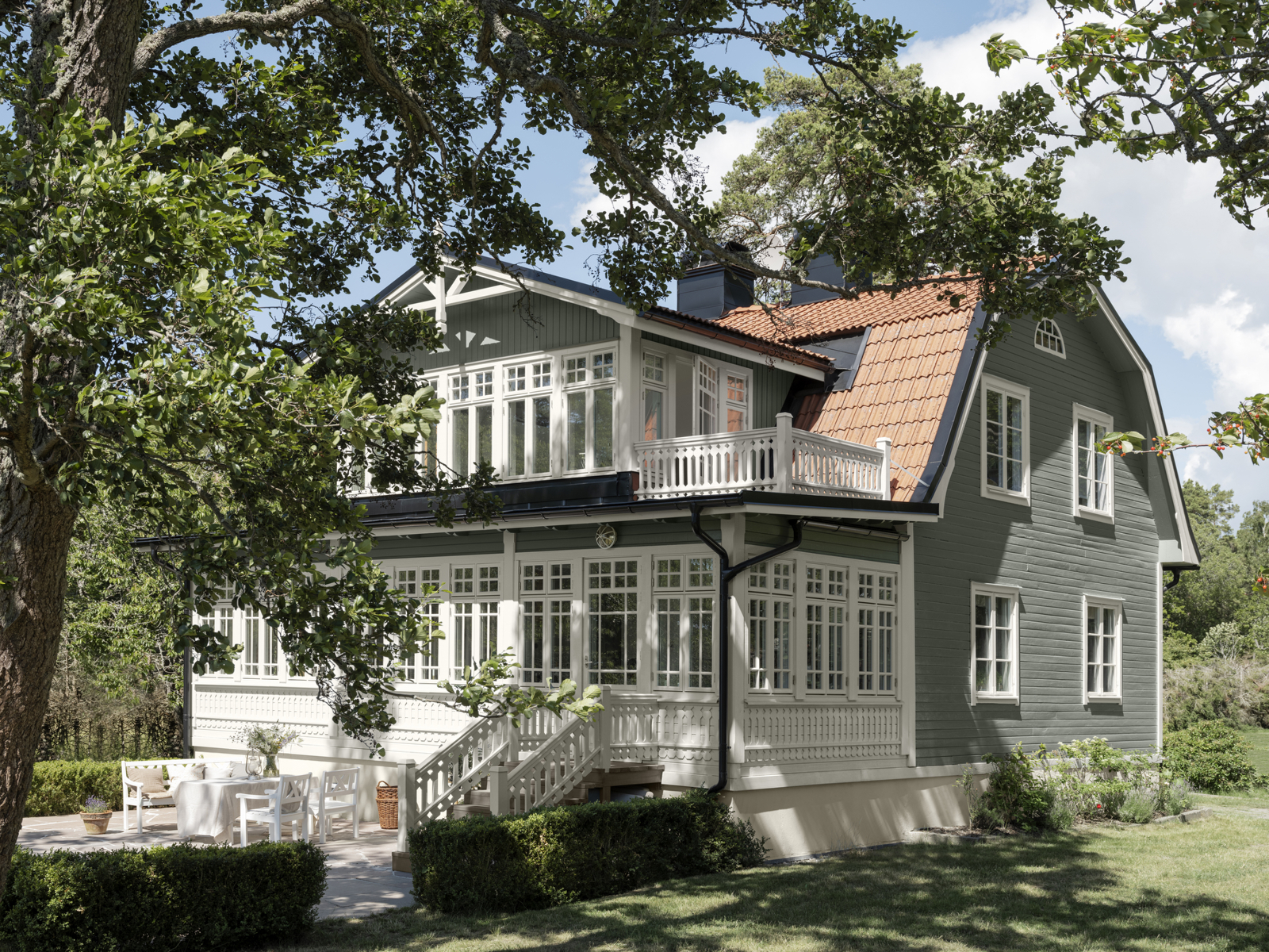 Grønt villahus, tre i forgrunnen. Foto.