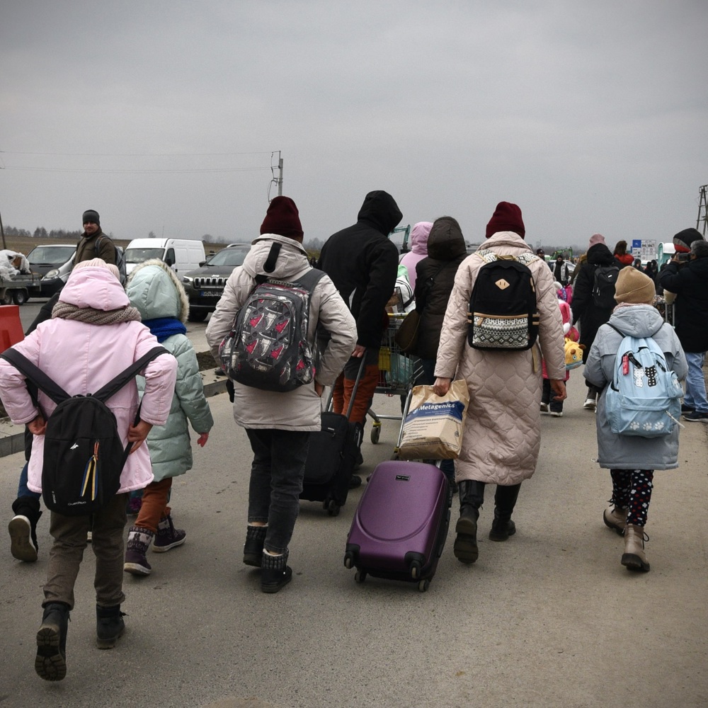 Flyktninger med ryggen til som har med seg bagasje