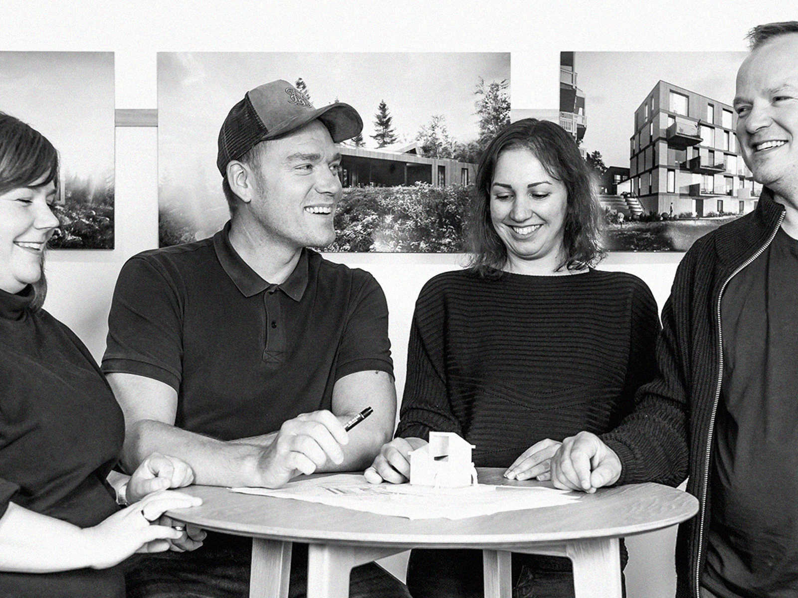 Gruppebilde av Tanken arkitektur, 4 mennesker stående rundt et høyt bord. Svart Hvitt. Foto.
