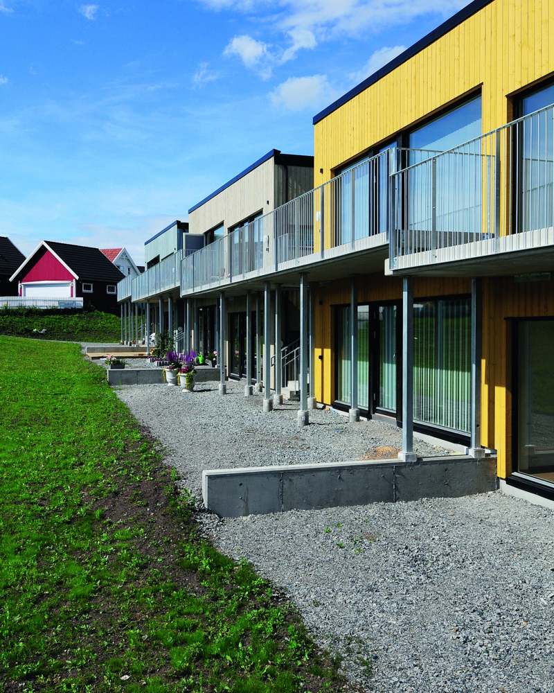 Eksteriør bilde, rekkehus i ulike farger, grus fremfor inngang. Foto.