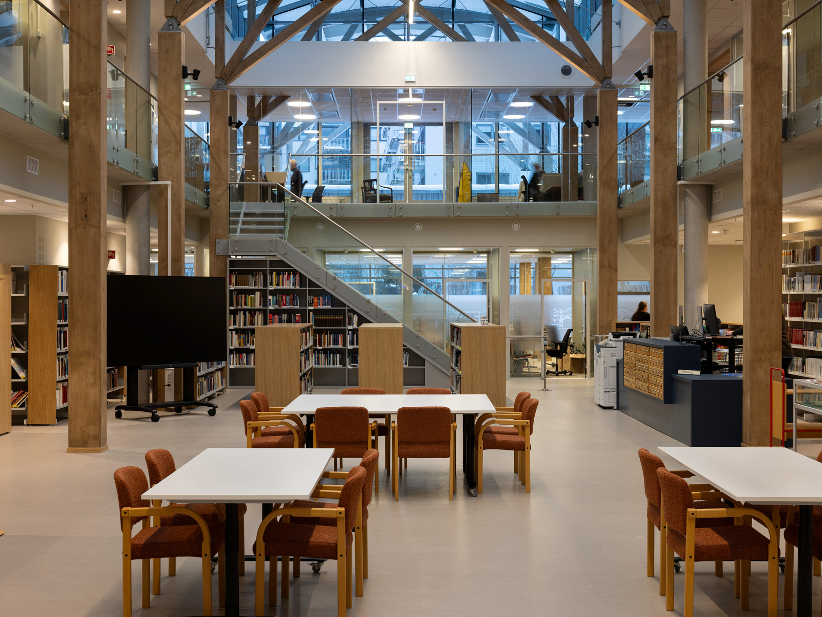 Interiør foto av et større åpent bibliotekrom, sittegrupper, trapp dobbelthøyt rom.