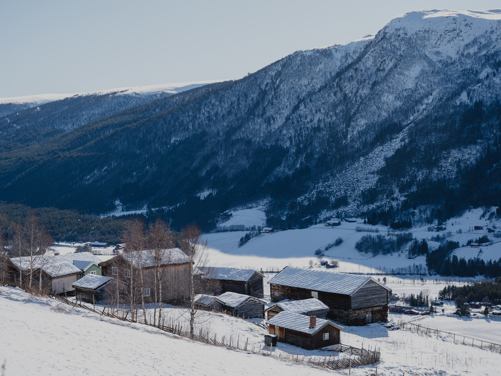 Foto av et eldre gårdstun i et vinterlandskap.