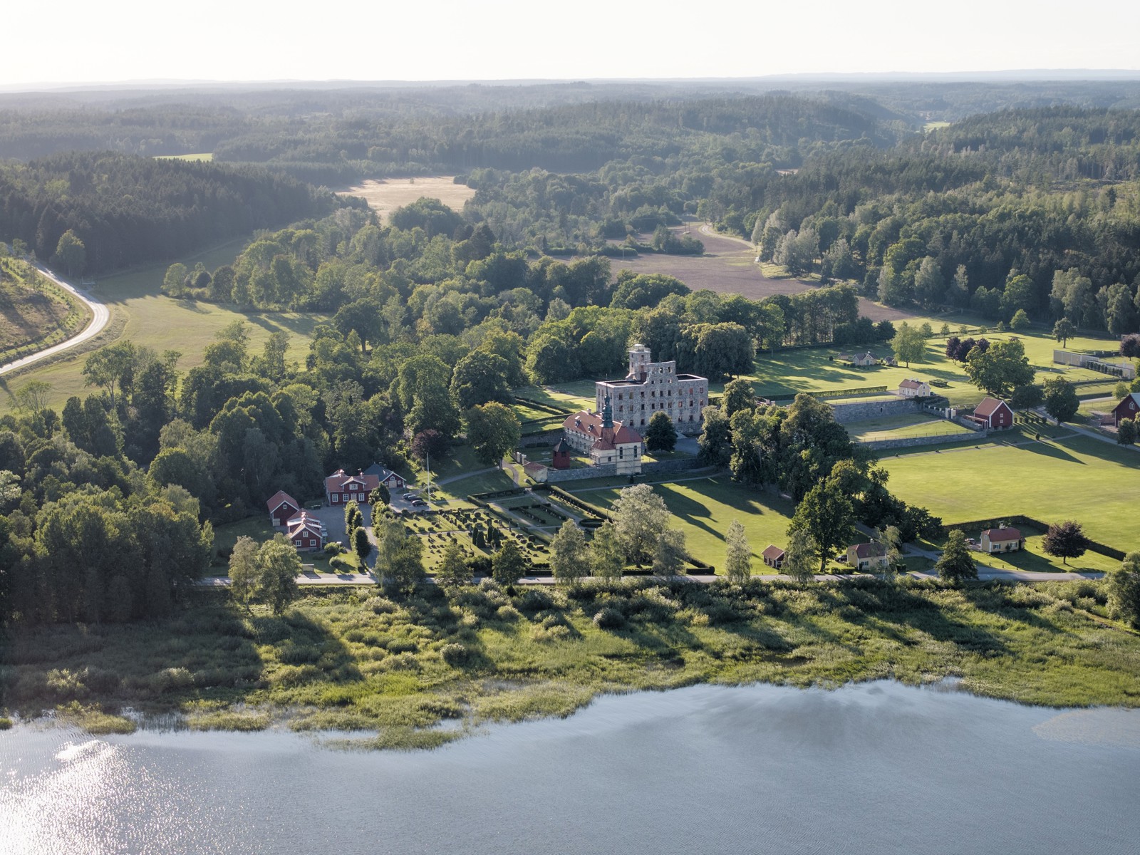 Oversiktsbilde som viser et slott i landlige omgivelser, vann i forgrunnen.