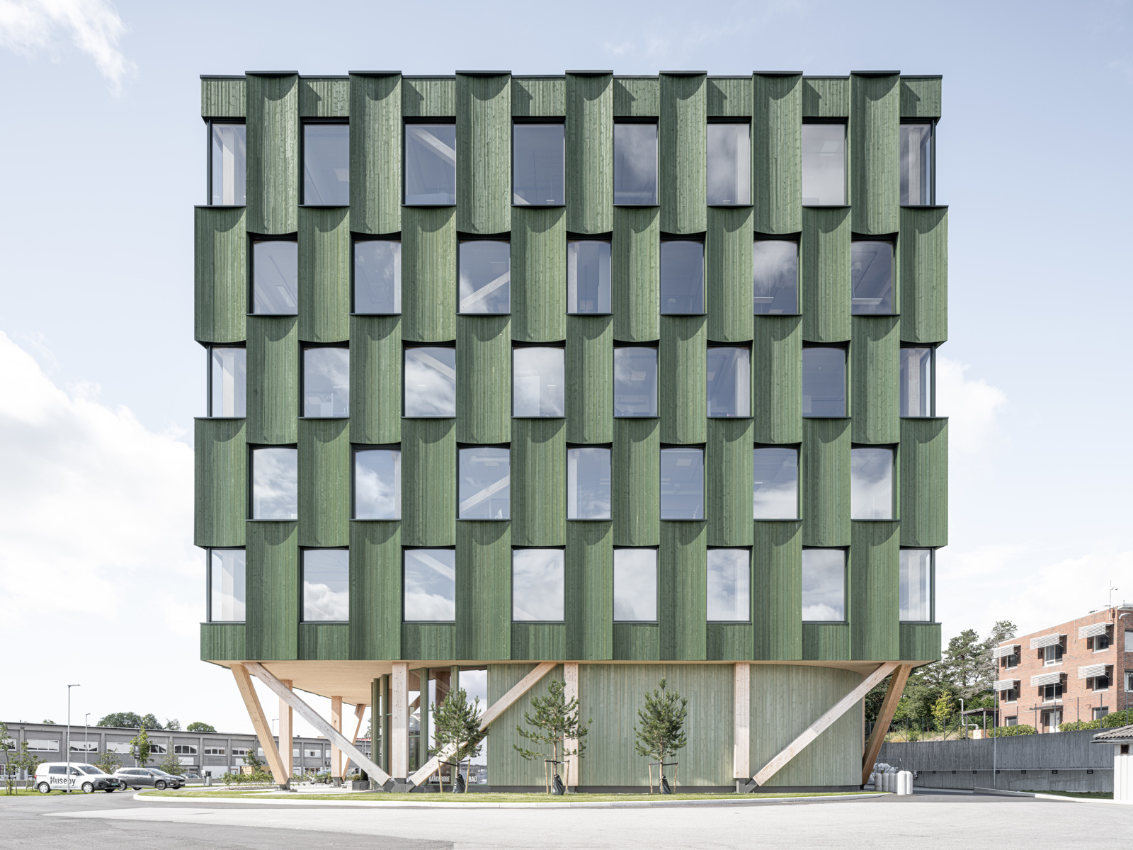 Foto av grønn fasade av treverk i bykontekst.