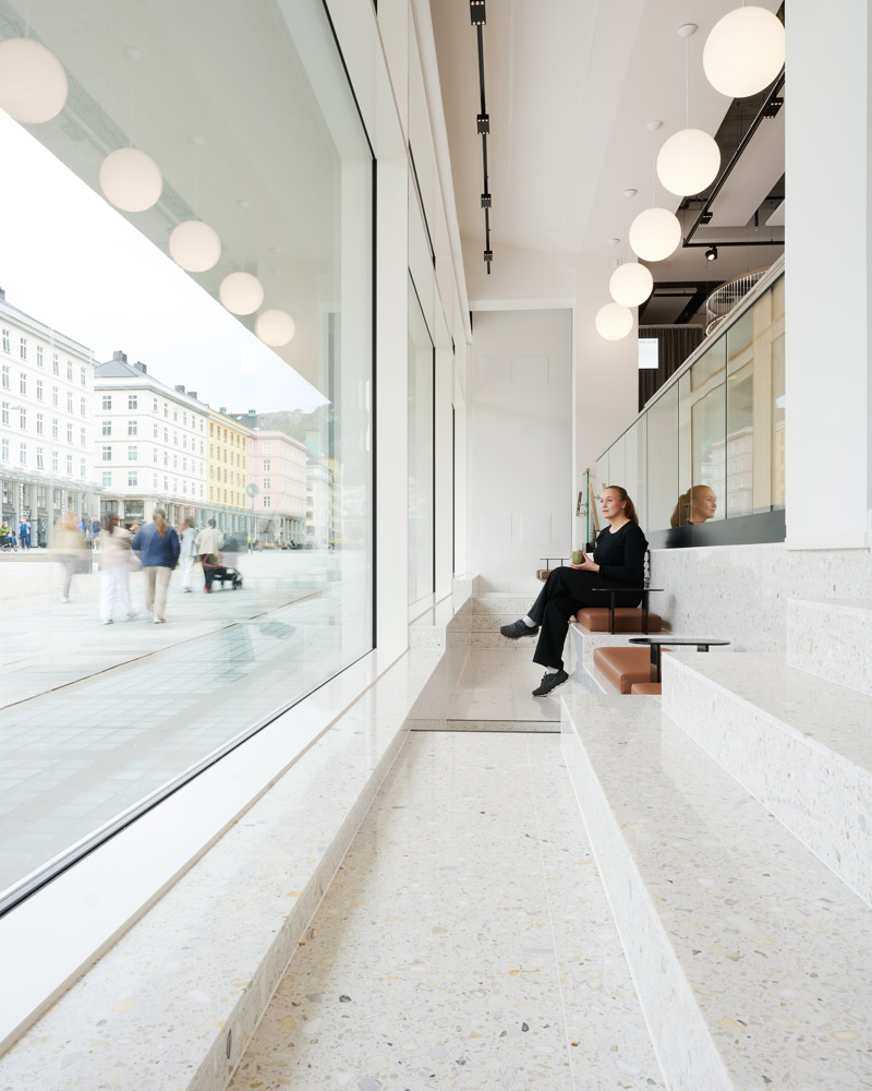 Interiørfoto som viser fasaden som åpner seg mot Torgallmenningen og drar dagslyset inn i lokalet