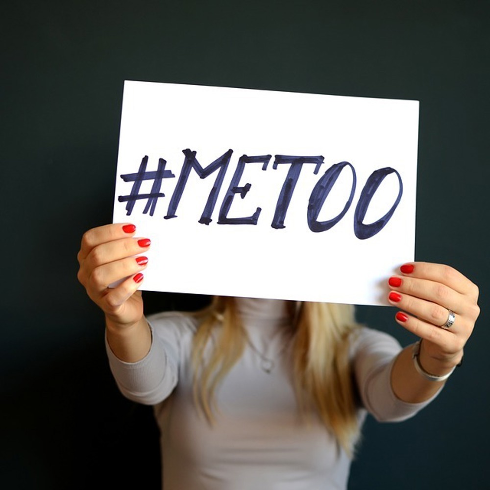 En person som holder en lap med teksten #metoo opp foran ansiktet