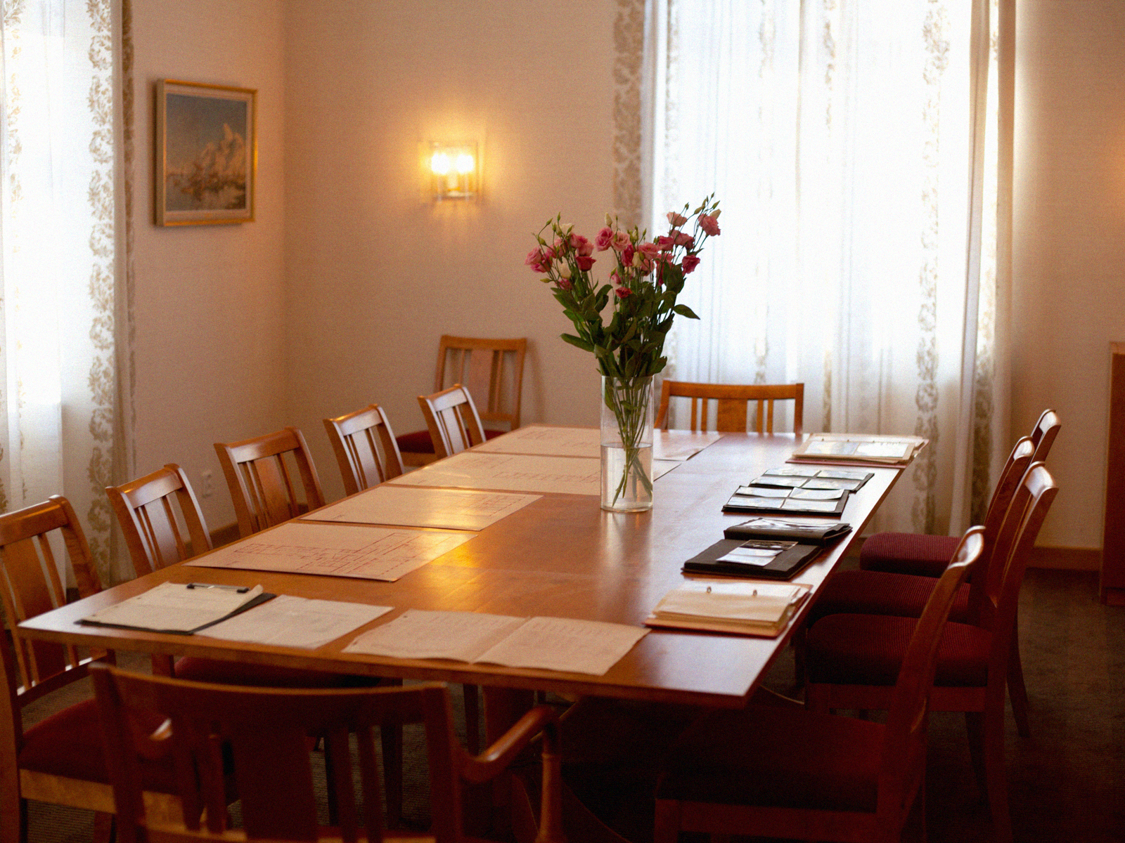 Bord med blomster i en vase og papirer liggende rundt