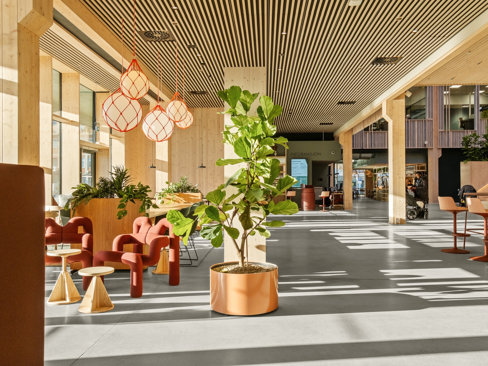 Interiør foto av første etasje på utdanningsbygg, med ulike sittesoner og åpne gangarealer.