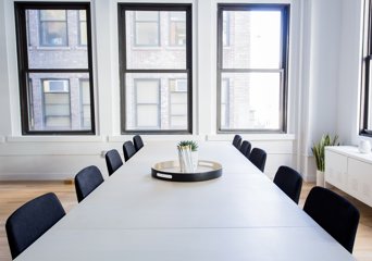 Illustrasjonsbilde av et kontorlokale med tomme stoler rundt et bord.