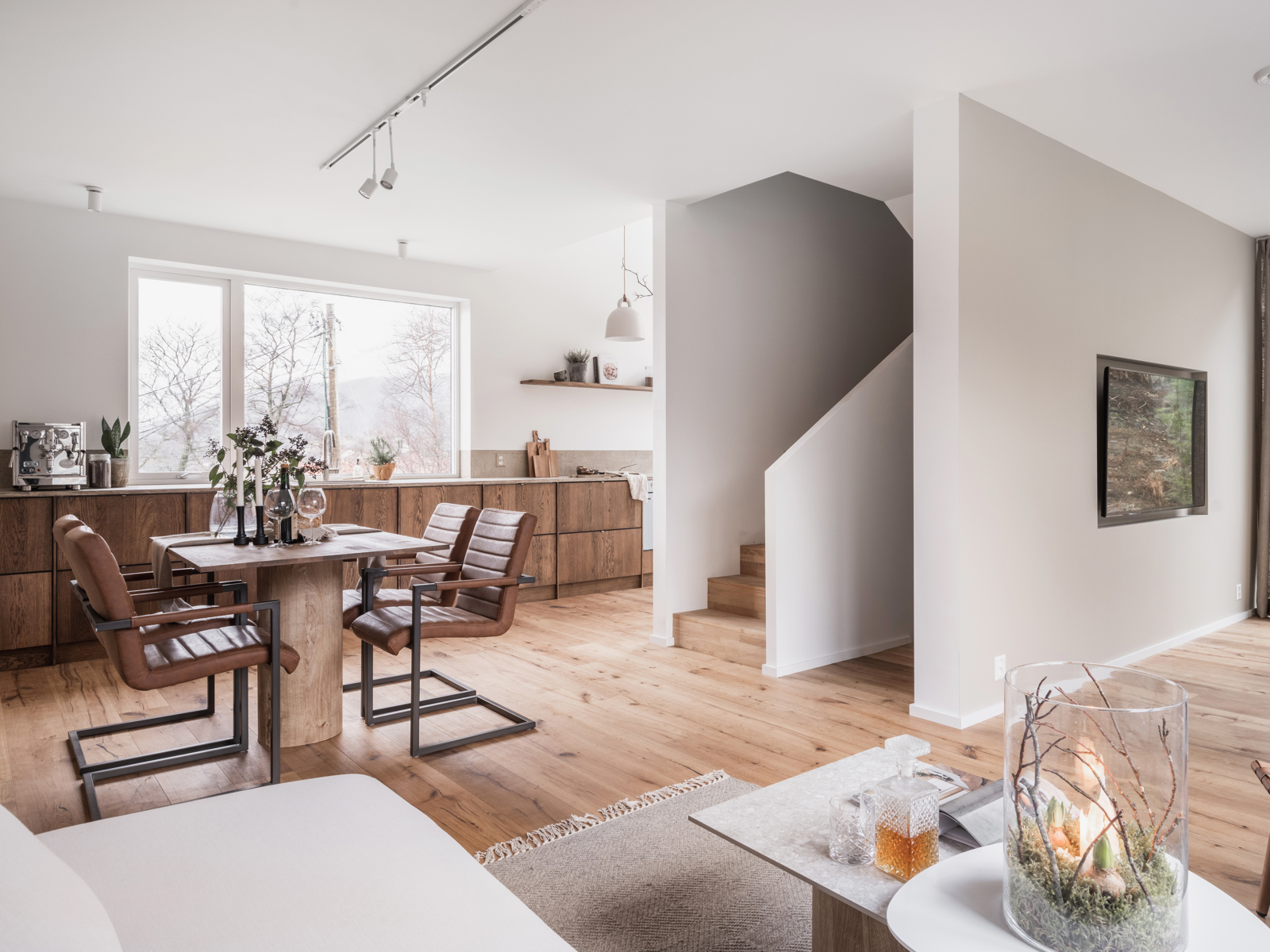 Interiør foto av åpen stue og kjøkken løsning, sittegruppe og trapp. 