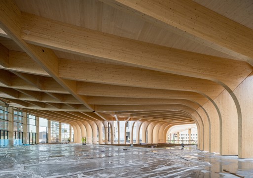 Byggeplass interiør, stort rom med trebjelker og tresøyler i limtre. Foto.