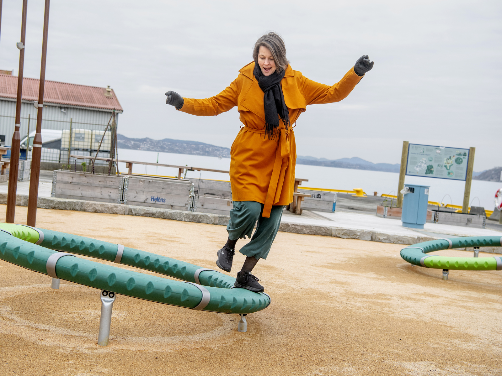 Voksen dame leker på et apparat ute på en lekeplass. Foto.