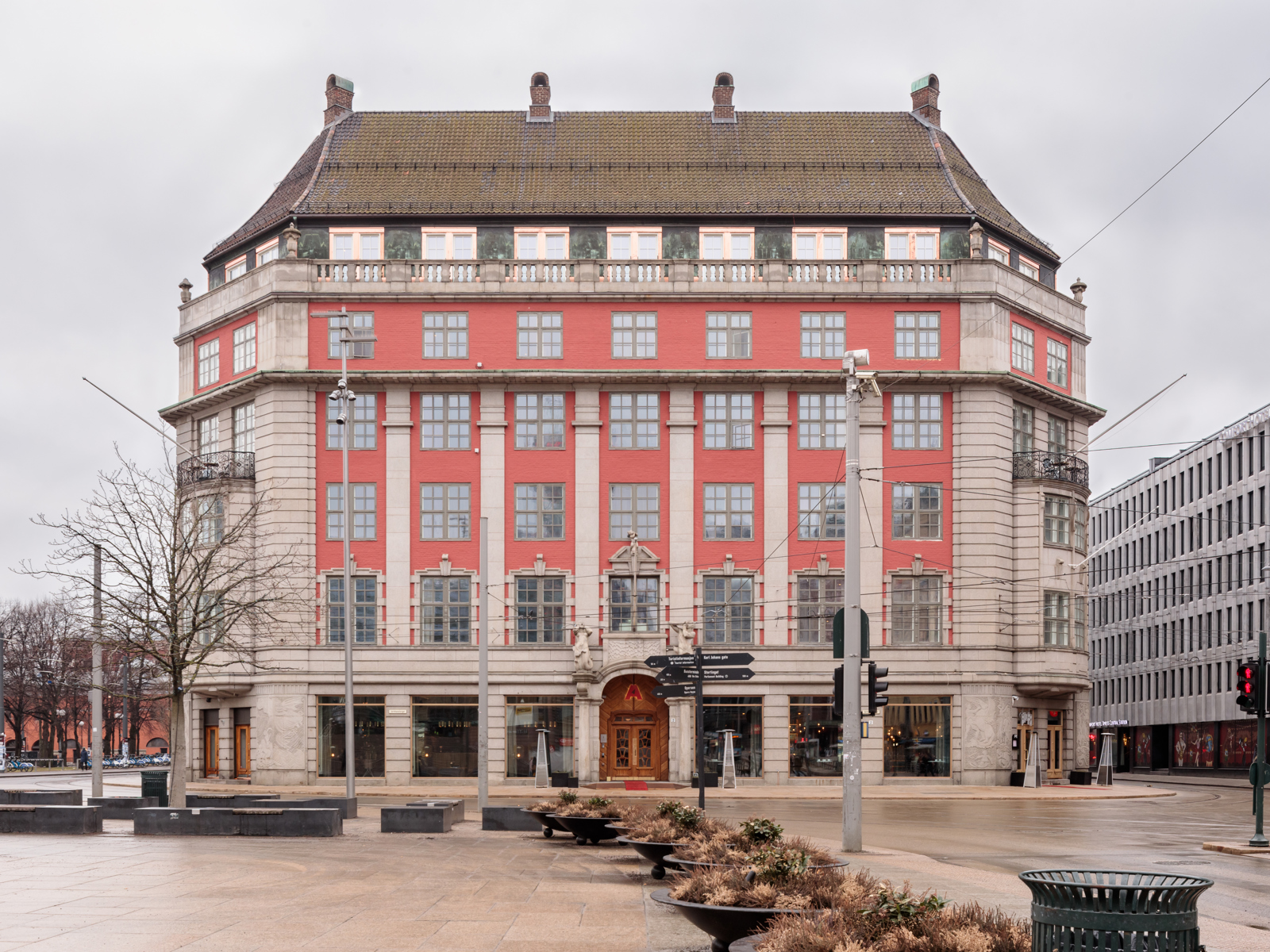 Foto av hotell i klassisk stil, rød og hvit fasade. Plass i forgrunnen.