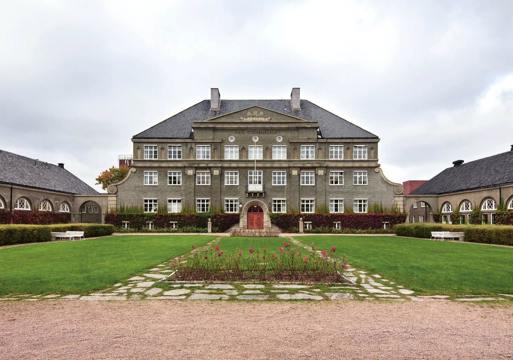 Tradisjonelt stort bygg med stor hage fremfor. Foto. 