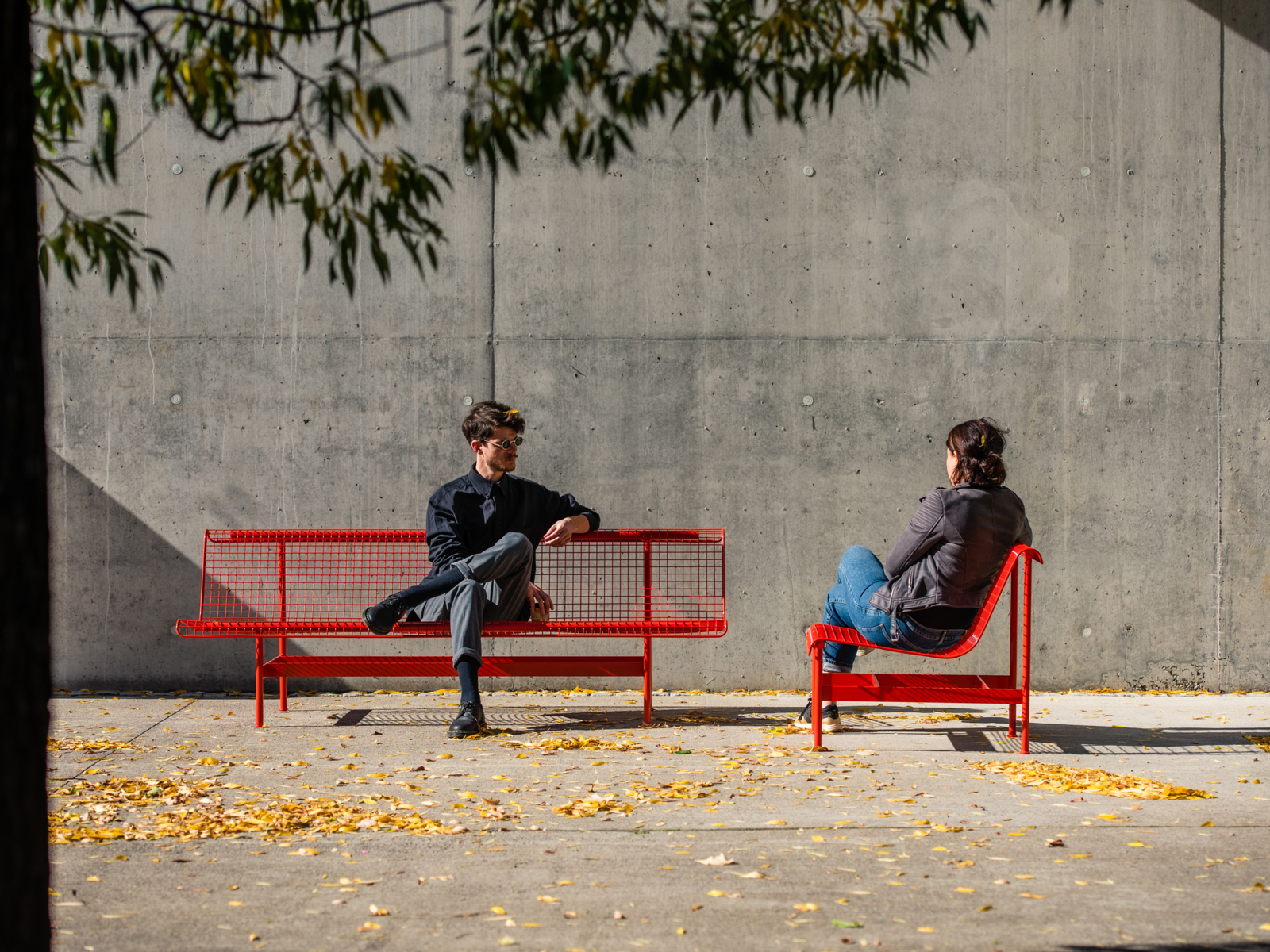 Personer som sitter på to røde benker