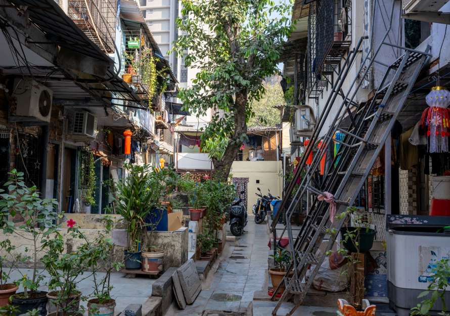 Foto av et fargerikt nabolag i Mumbai med mye planter og personlige gjenstander.