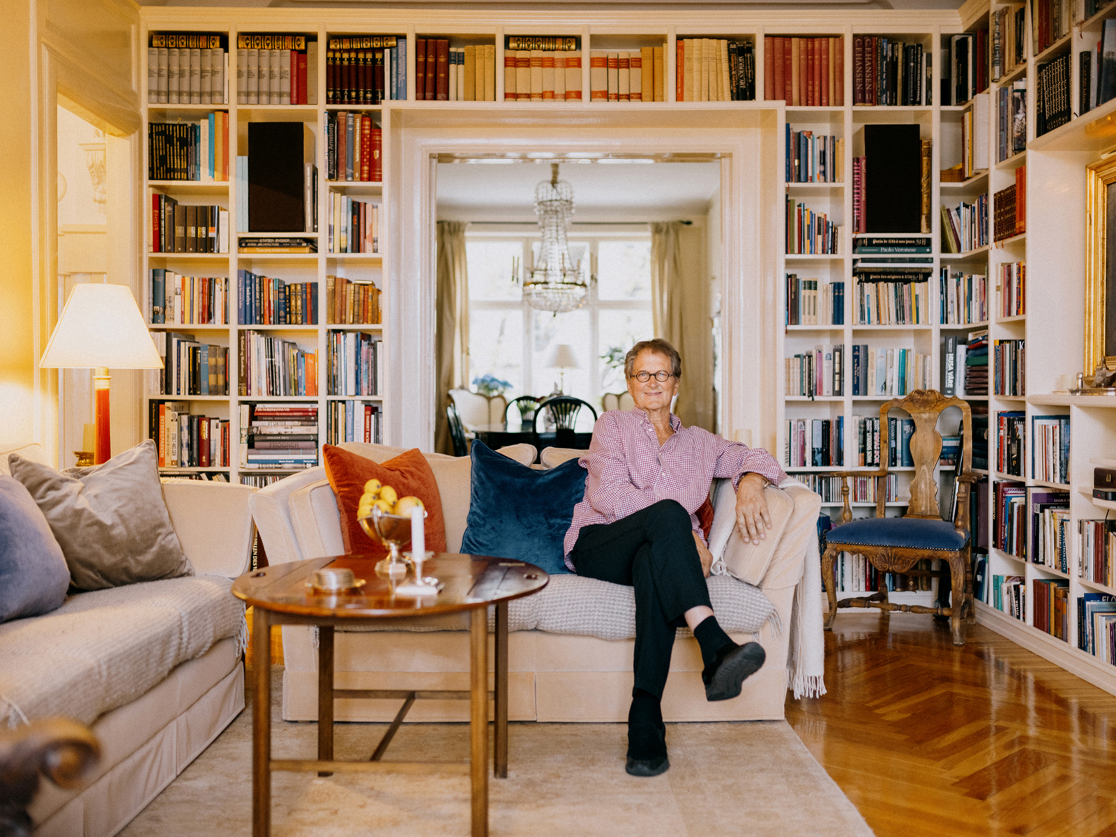 Thomas Thiis-Evensen  sitter i en sofa med bokhyller på veggene rundt. Foto. 