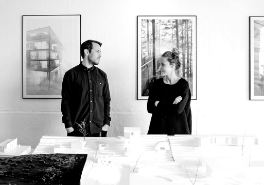 Sanden+Hodnekvam står bak et bord med en arkitekturmodell. Foto.
