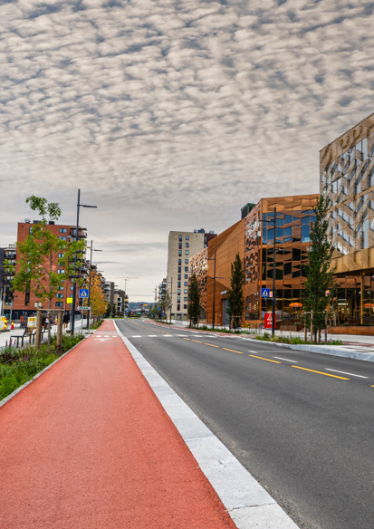 Foto av gateløp med rødt sykkelfelt, bilvei og blokker på høyre side.