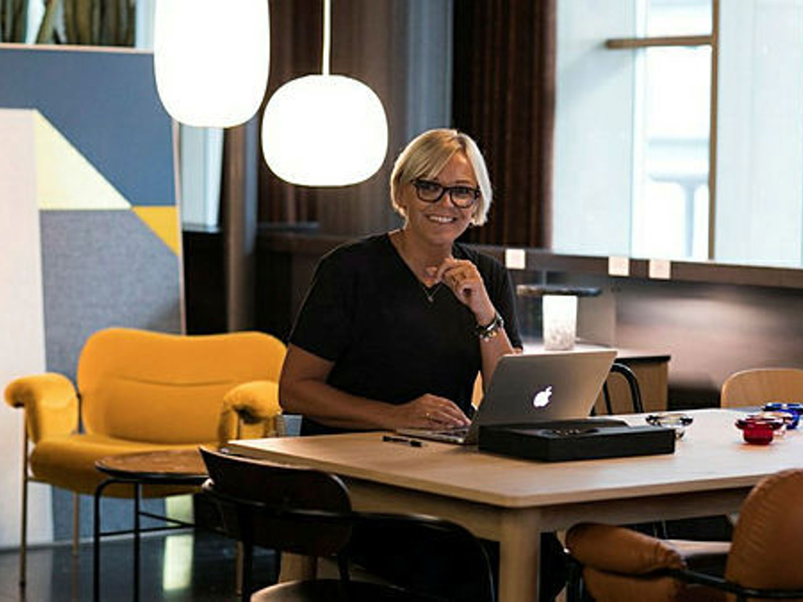 Ragnhild Grytten sitter ved et bord og jobber på PC'en. Foto.