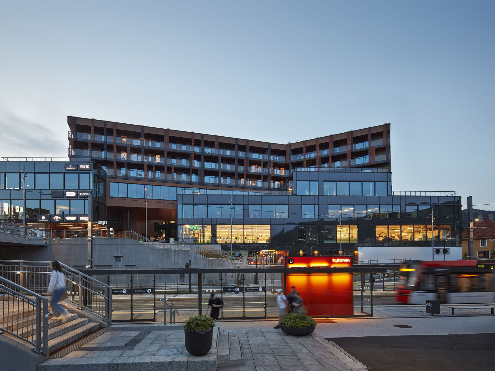 Fasade foto av bygg i bysituasjon, t-bane i forgrunn.