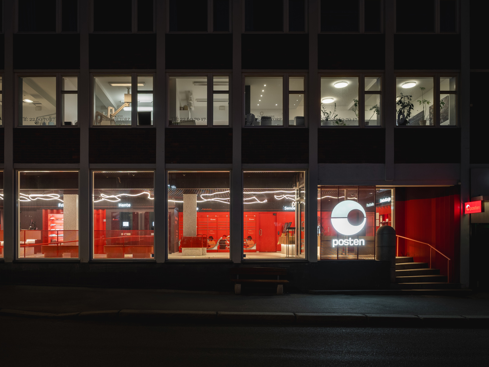 Fasade foto av posten flagship bygg opplyst fra innsiden i kveldsmørket.