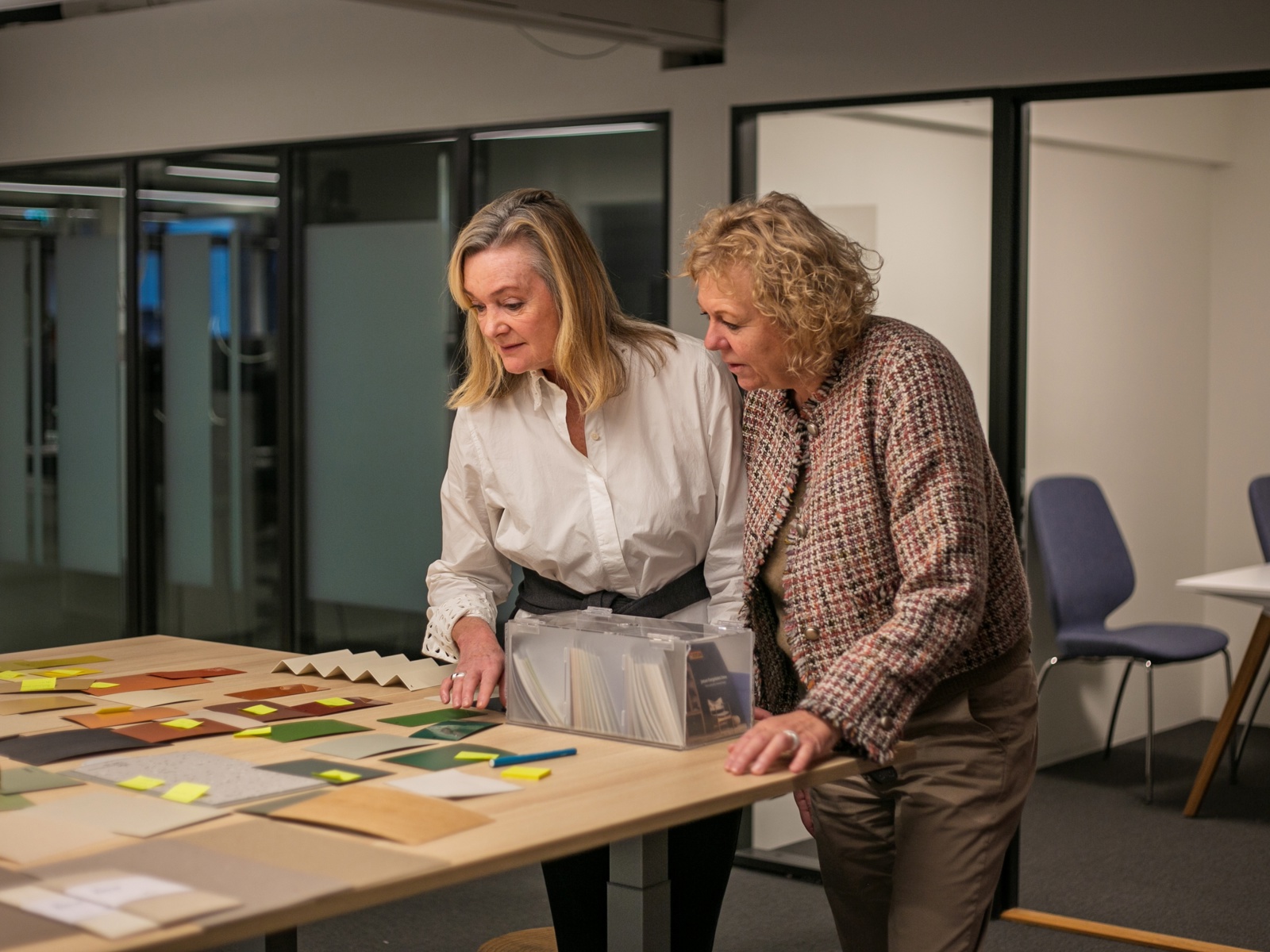 Foto av Hanne Hemsen og Nina Kristiansen som står over et bort og ser på fargeprøver.