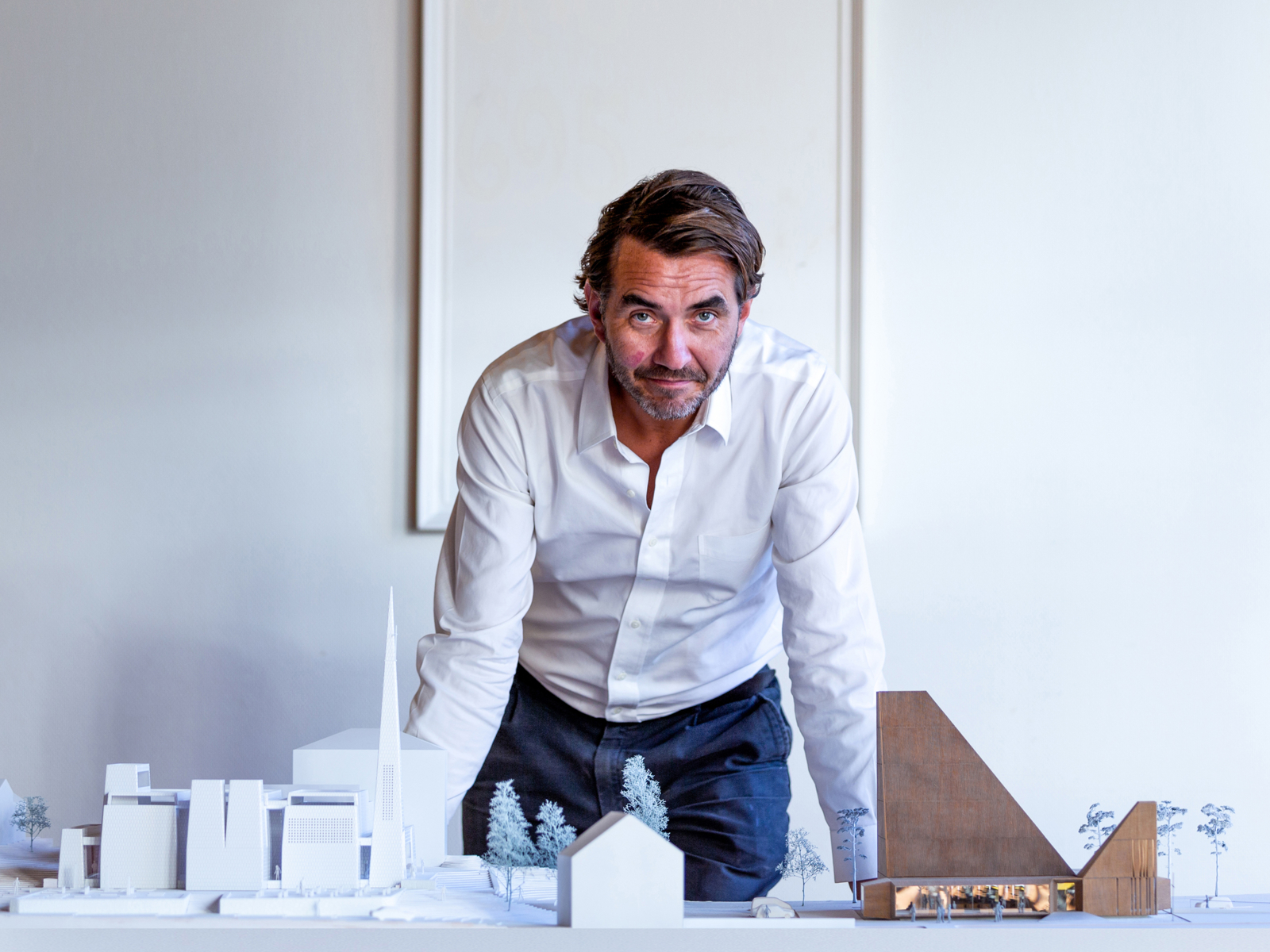 Espen Surnevik lener seg over et bord med arkitekturmodeller på. Foto.