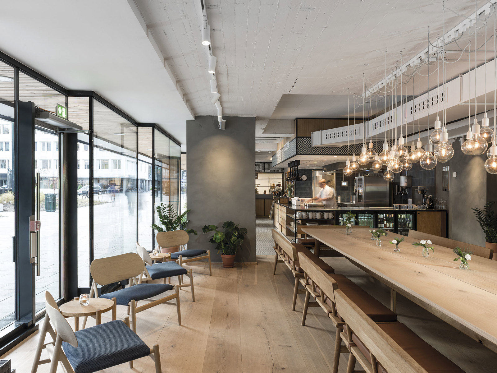 Interiørfoto av restaurant med langbord og mindre sittegrupper.
