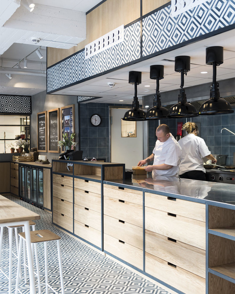 Interiørfoto av restaurant med disk og åpent inn til kjøkken.