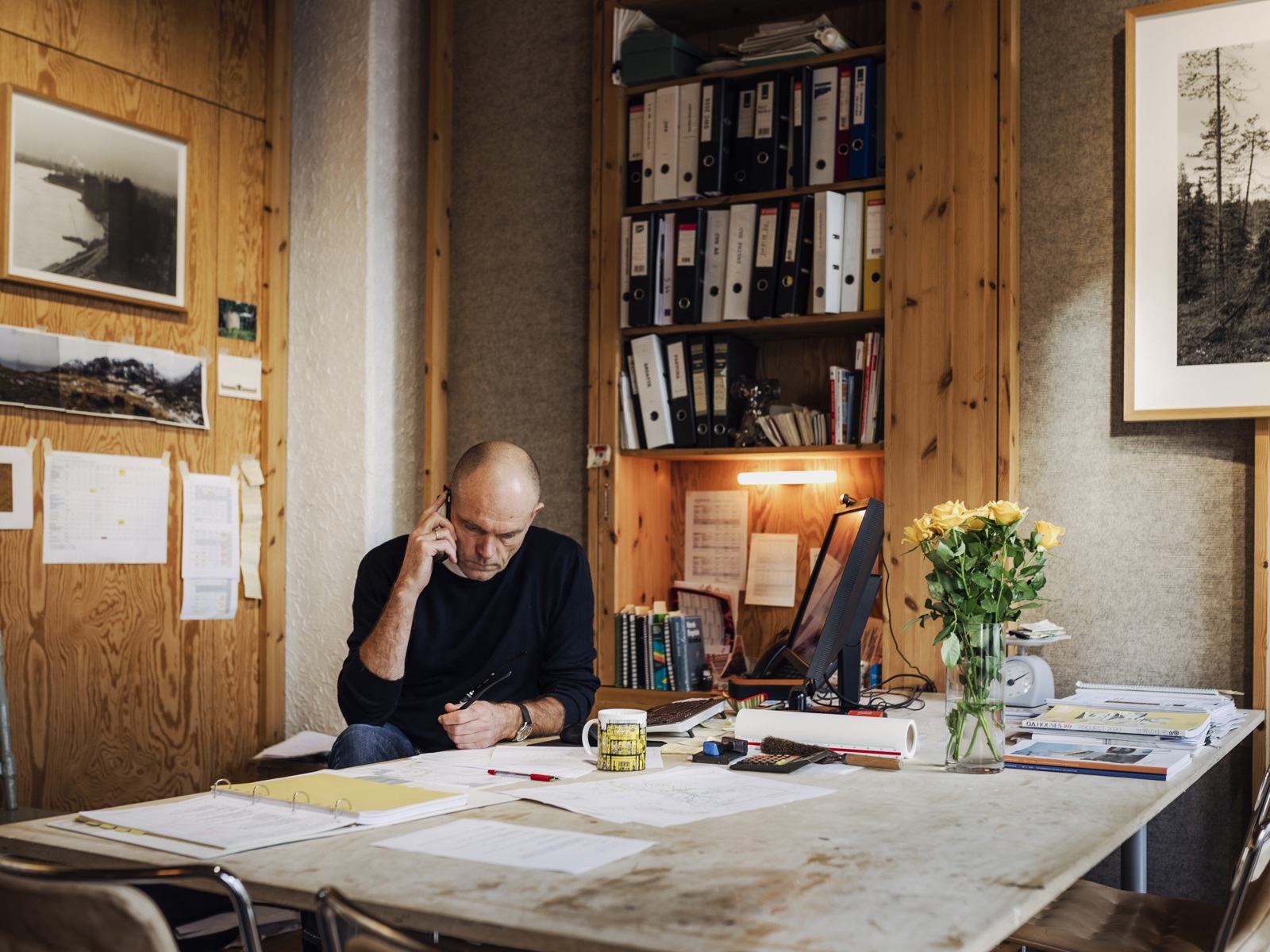 Carl-Viggo Hølmebakk sitter bak et skrivebord og snakker i telefonen. Foto.